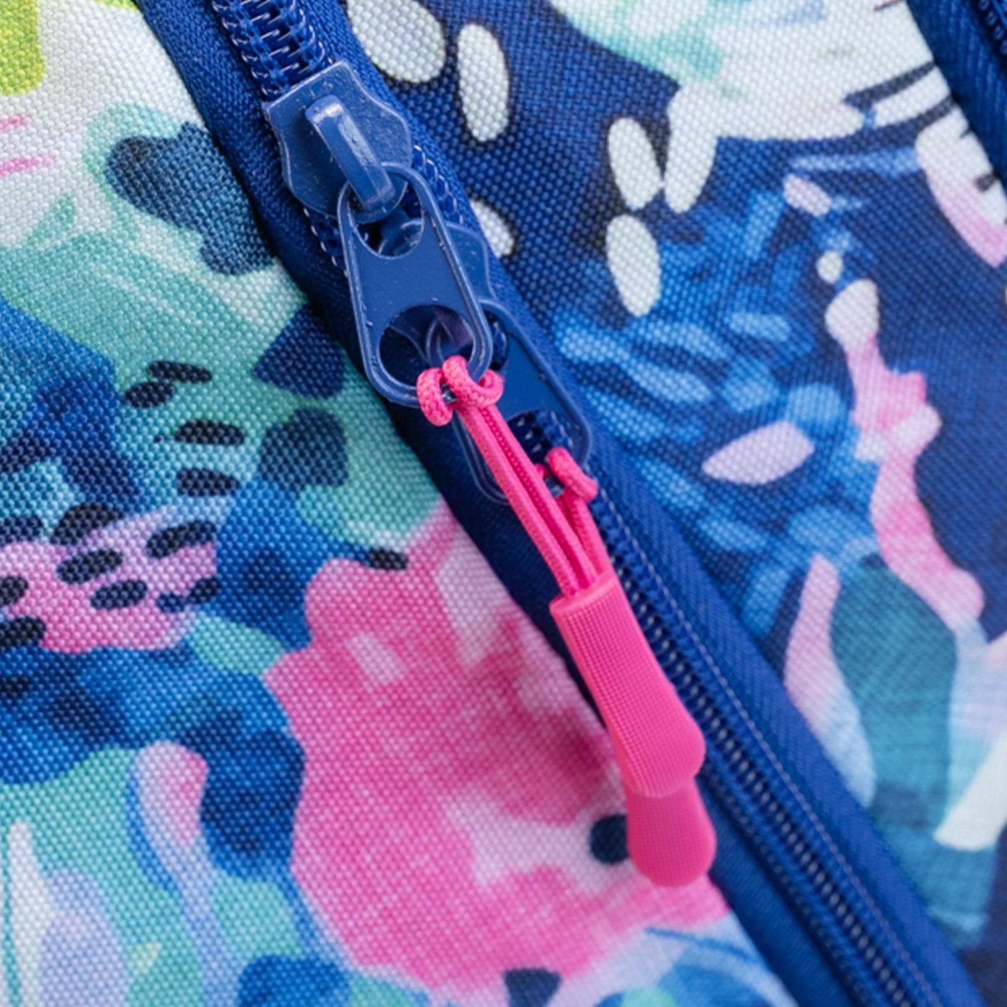 Bag close-up showing blue zip with pink zipper pull on blue and pink abstract floral patterned polyester fabric