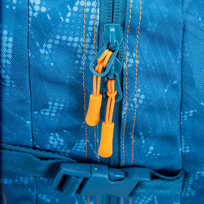 Backpack close-up showing dual zipper pulls with orange cord pulls on blue patterned nylon fabric with orange stitching and teal buckle