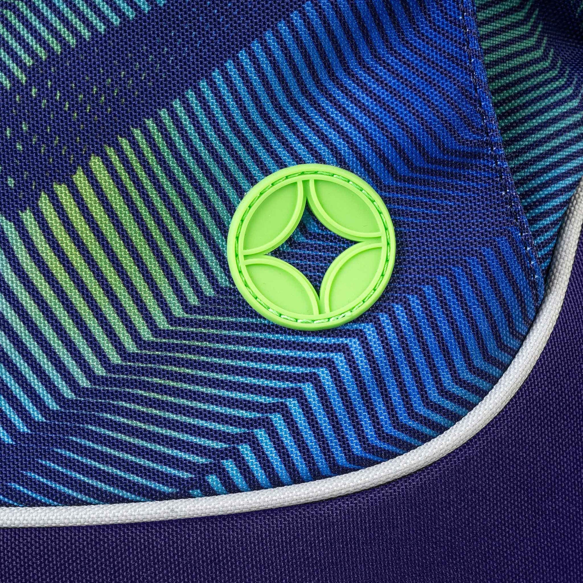 Cap brim close-up with blue green chevron stripe pattern and neon green rubber logo badge with white piping trim