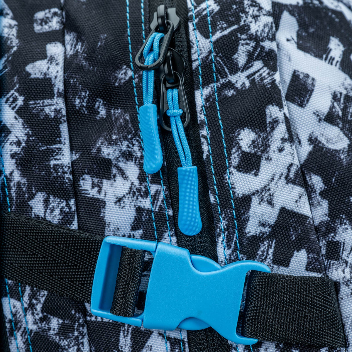 Backpack close-up showing blue zip pullers, buckle clip and blue topstitching on black-white graphic print fabric